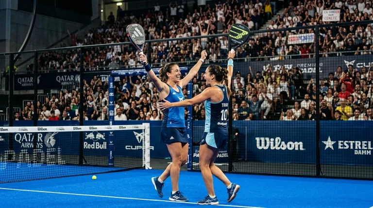 Pareja femenina celebrando un punto en una pista de pádel del Premier Padel con público de fondo